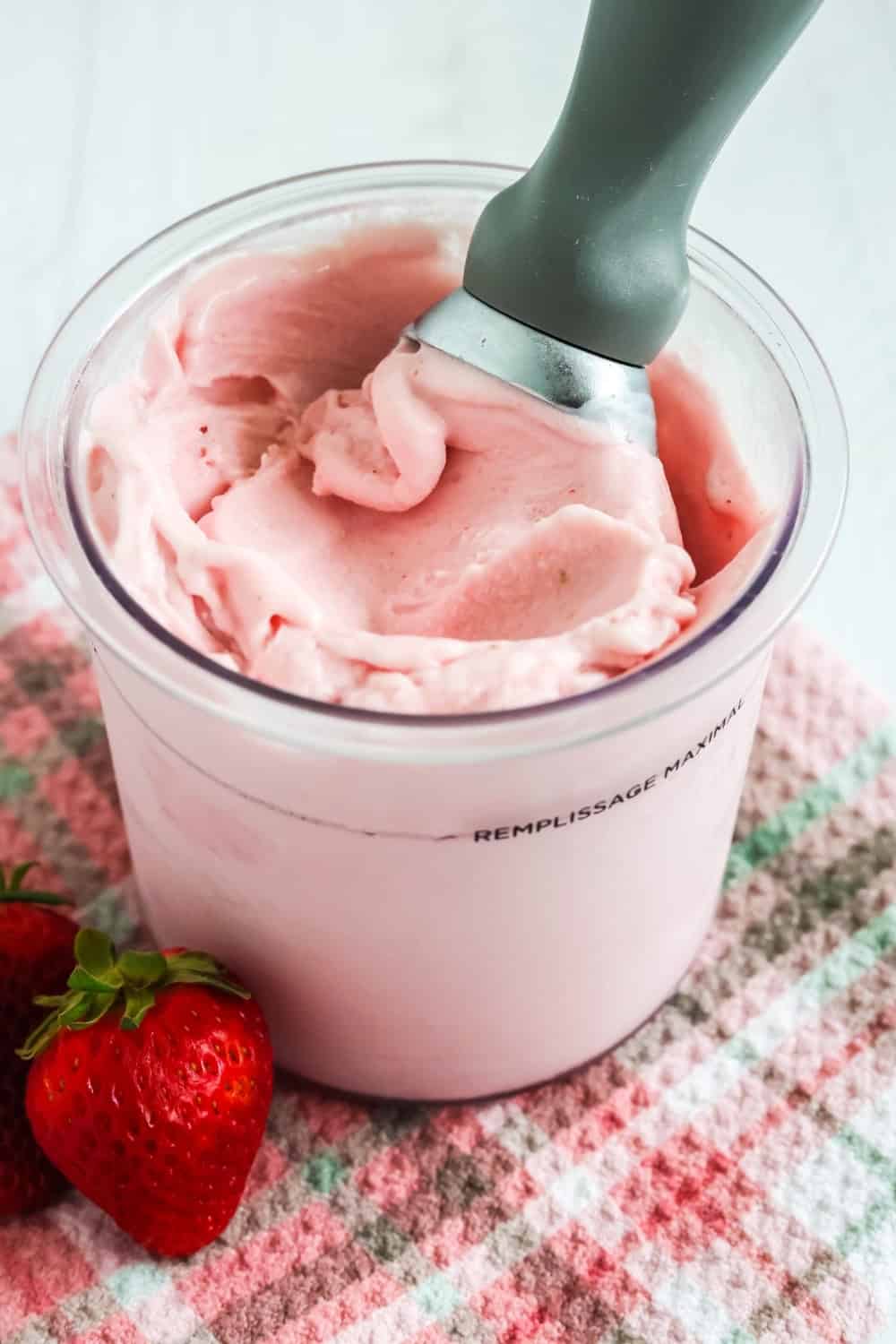 pint of homemade strawberry gelato made in the Ninja Creami machine. A scoop is in the pint.