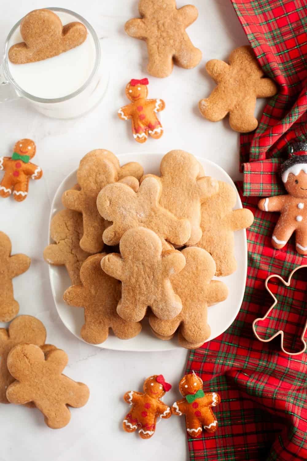 overhead view of a white plate with several cake mix gingerbread cookies on it. There are several additional cookies scattered around the plate, along with gingerbread decor.