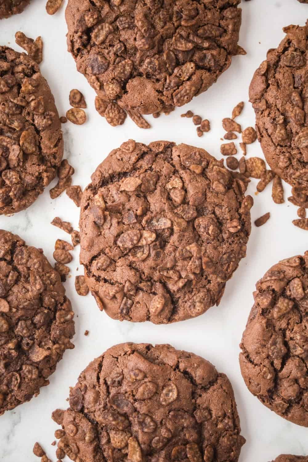 overhead view of several cocoa pebbles cookies, with cereal scattered around them.