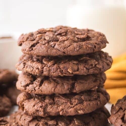 stack of Cocoa Pebbles cookies in front of a glass of milk.