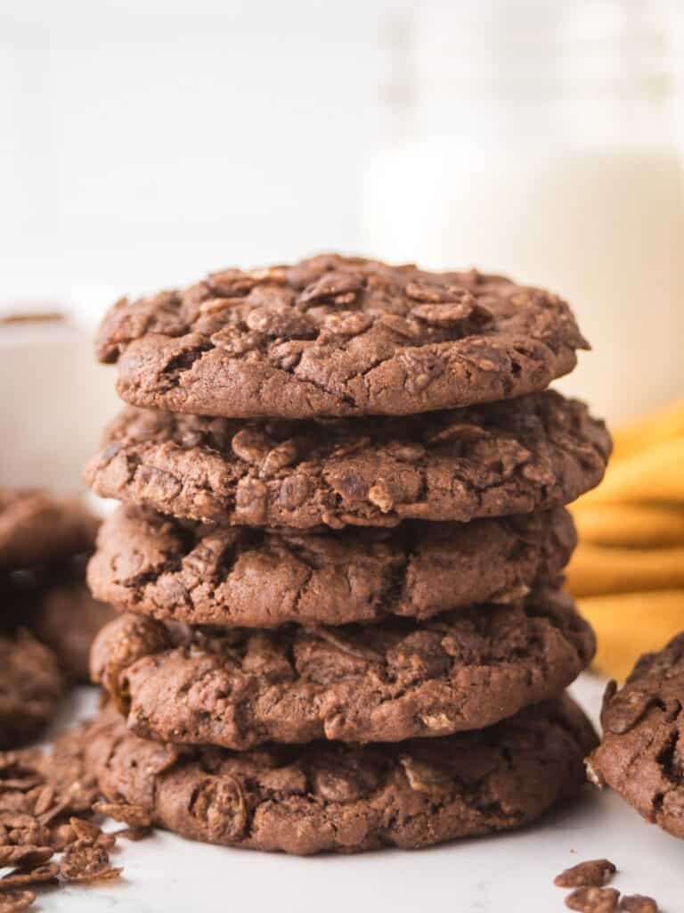 stack of Cocoa Pebbles cookies in front of a glass of milk.