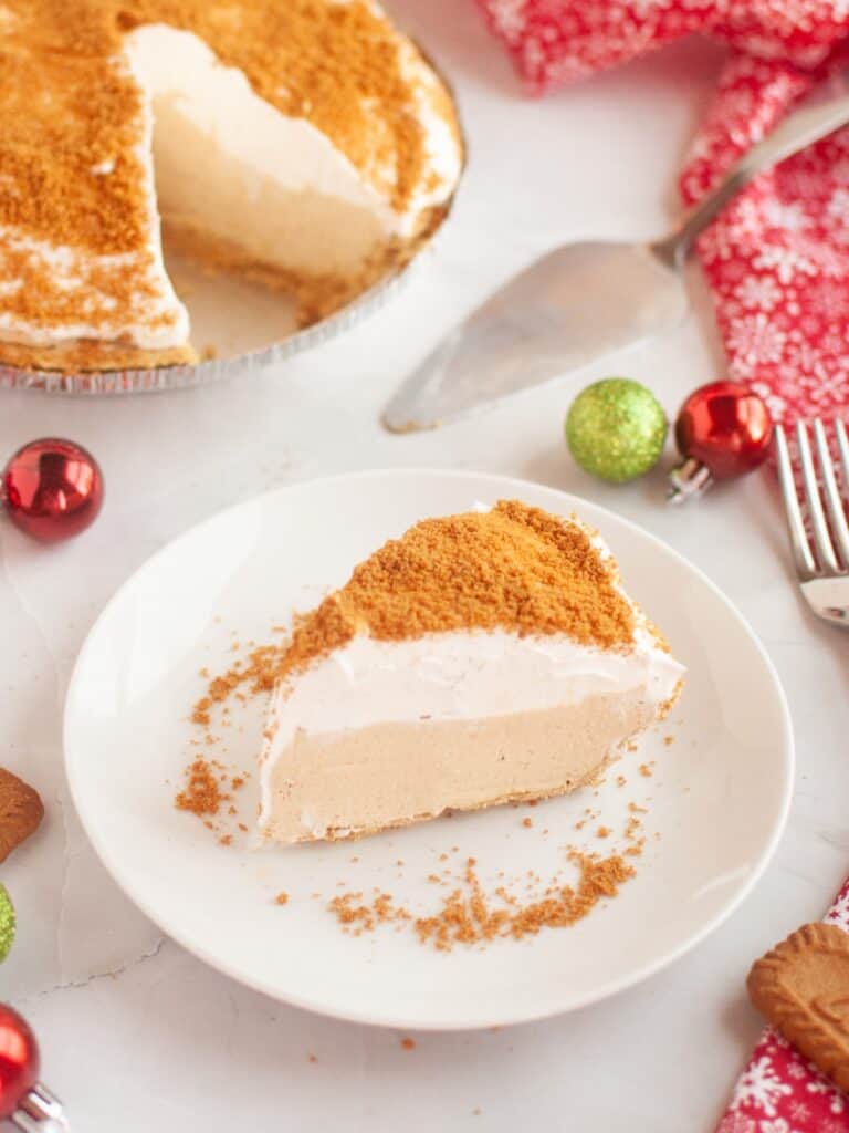slice of no bake gingerbread cream pie served on a white plate, with the rest of the pie in the background.