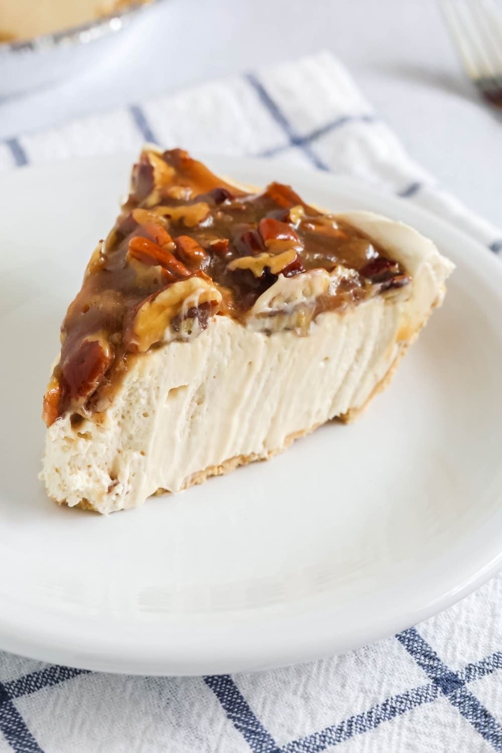 close-up view of a slice of fluffy, creamy no-bake pecan pie cheesecake on a white plate.