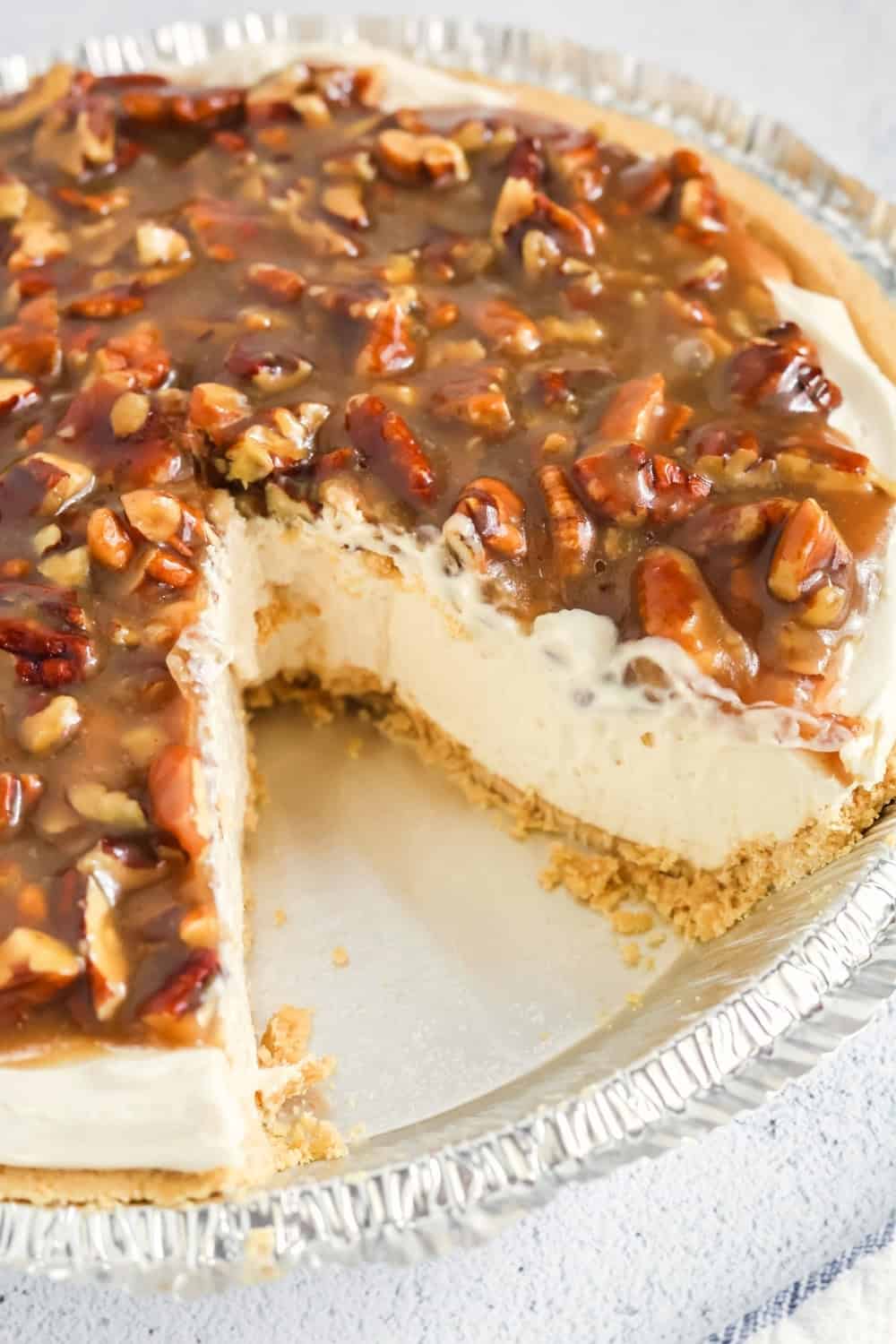 a sliced pecan pie cheesecake with a piece removed from the pie plate.