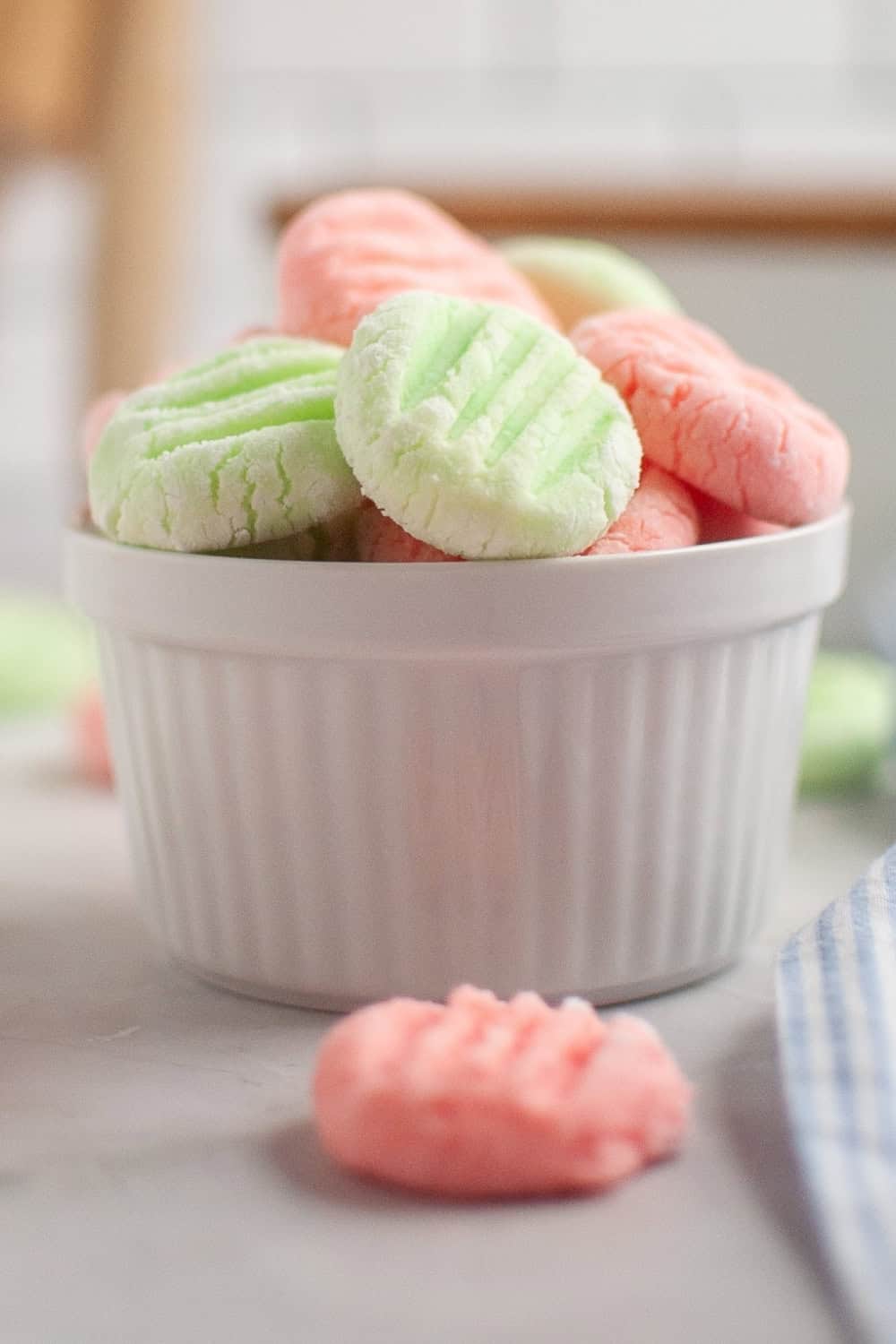 side view of a white bowl serving homemade cream cheese mint candies.