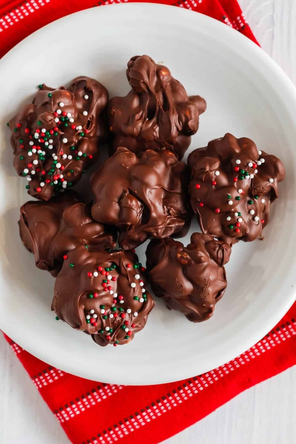 overhead view of sugar free Christmas peanut clusters served on a white plate.