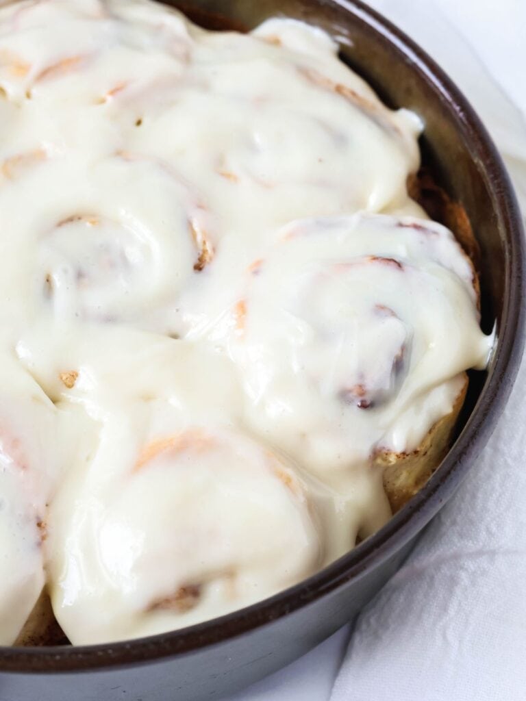 Bisquick cinnamon rolls, topped with cream cheese icing, in a round cake pan.