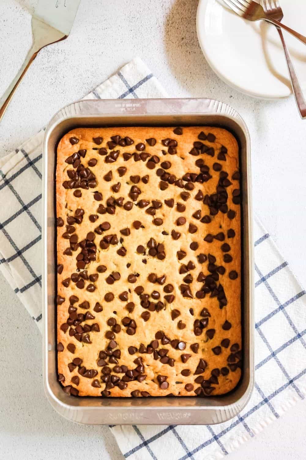 overhead view of an aluminum 9x13" baking pan filled with vanilla pudding dump cake topped with chocolate chips.