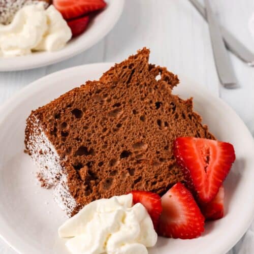 slice of chocolate angel food cake from a mix served on a white plate with berries and cream.