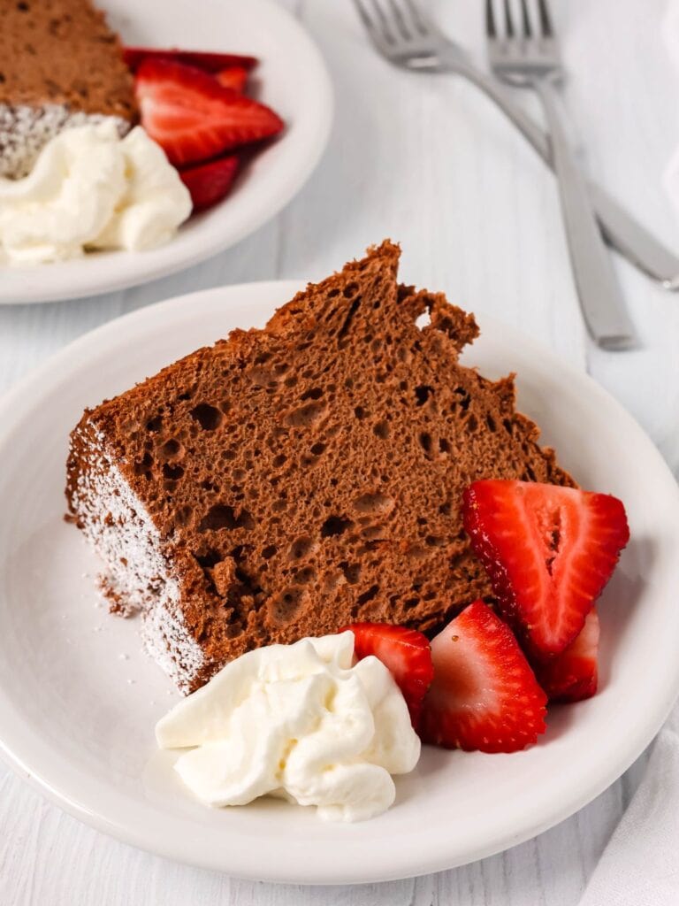 slice of chocolate angel food cake from a mix served on a white plate with berries and cream.