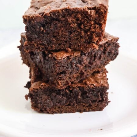 three chocolate pudding brownies stacked on top of each other on a white plate.