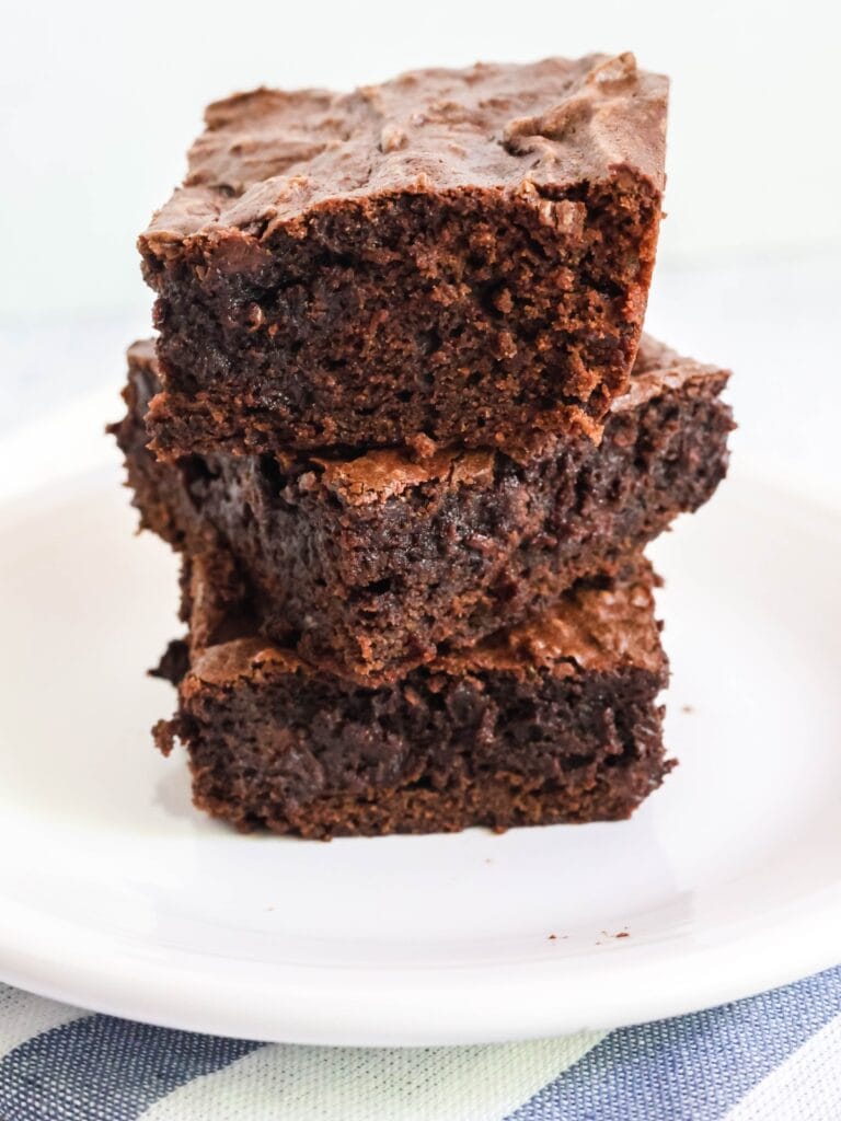 three chocolate pudding brownies stacked on top of each other on a white plate.