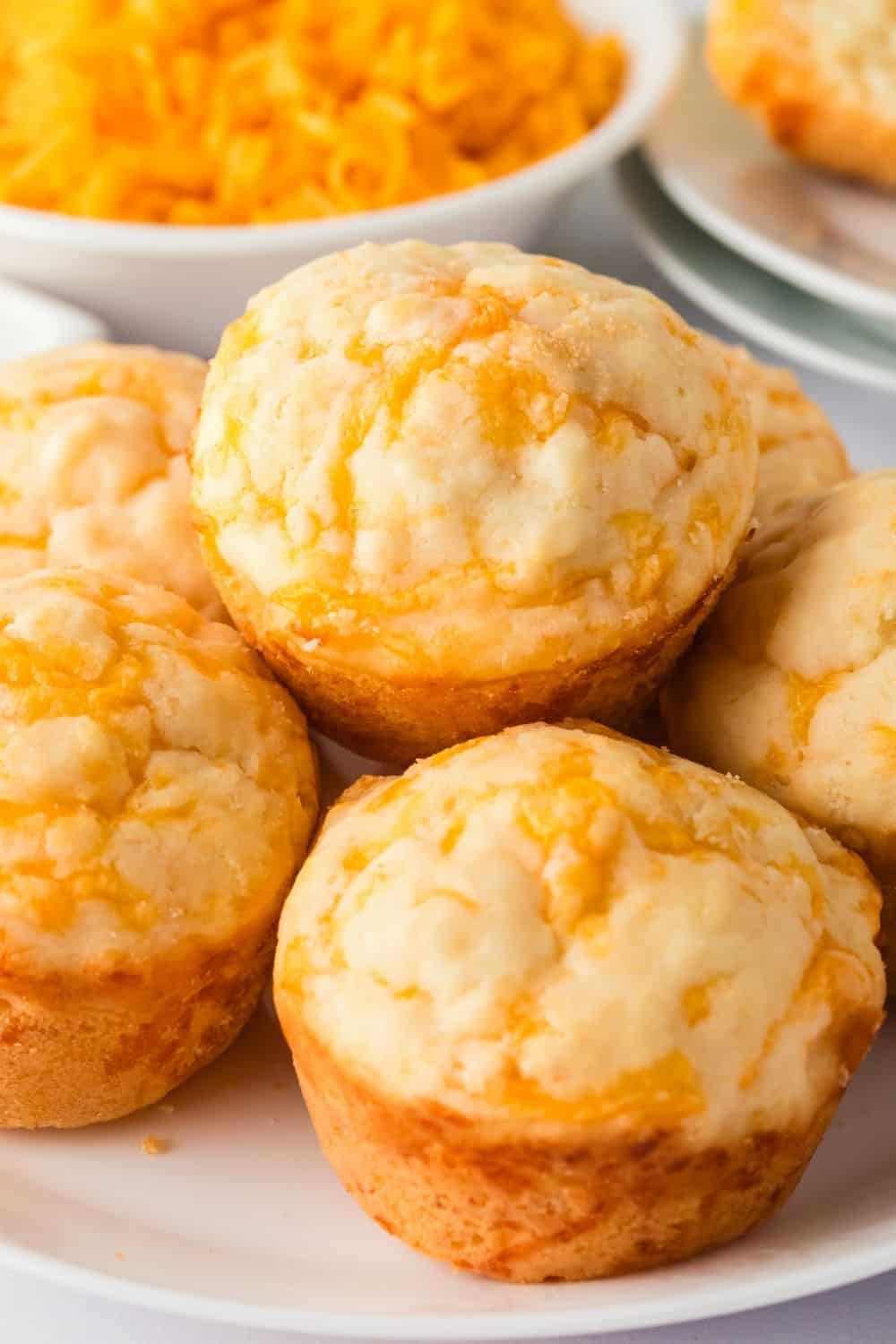 Close-up view of a few cheesy muffins made with Bisquick served on a white plate.