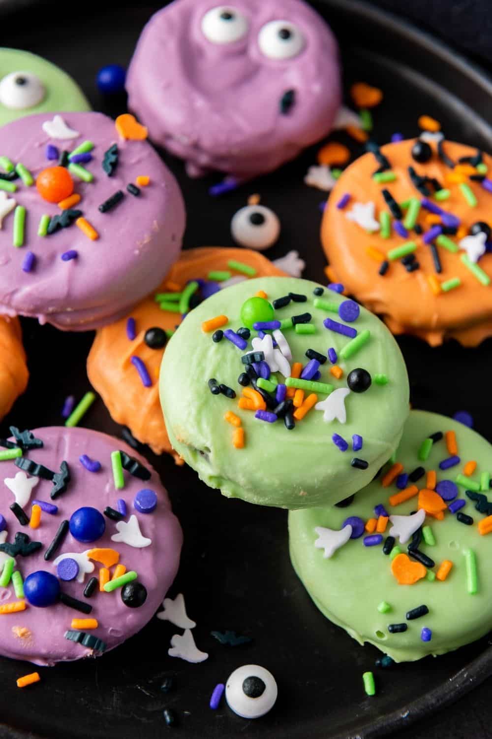 Colorful dipped Oreos decorated with Halloween sprinkles.