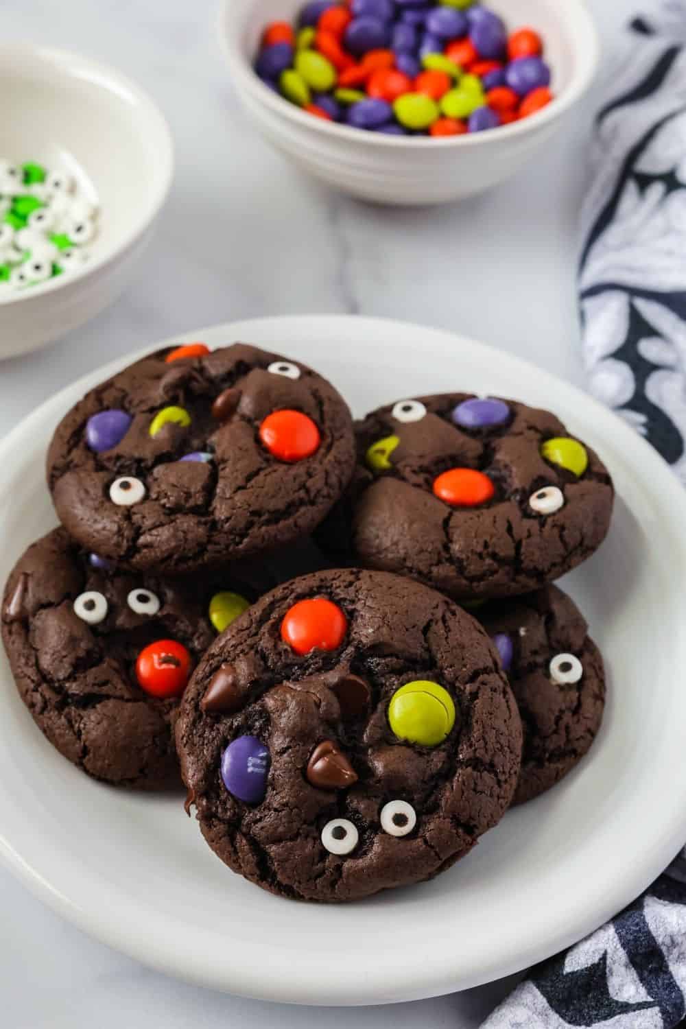 Five Halloween M&M chocolate cookies served on a white plate.