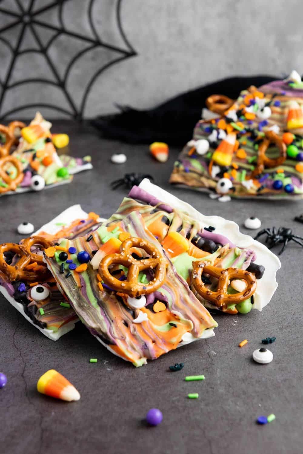 several pieces of Halloween candy bark, showing the colorful swirls, pretzel pieces, and candy bits in the bark.