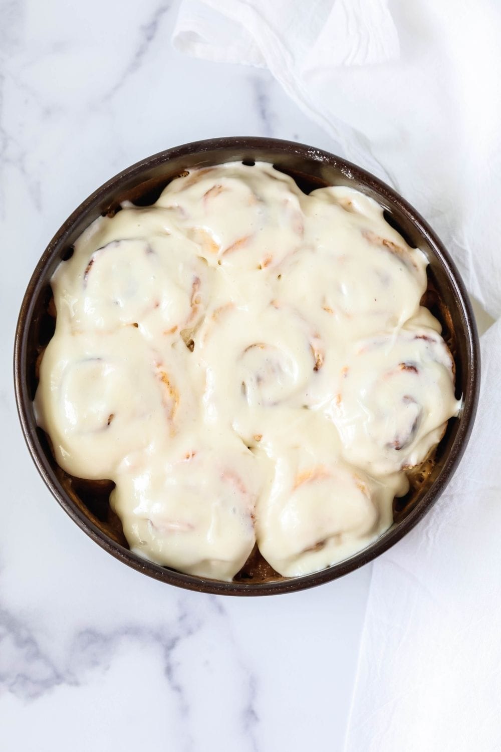 overhead view of a round pan of cinnamon rolls that were made with Bisquick baking mix. The rolls are topped with icing.