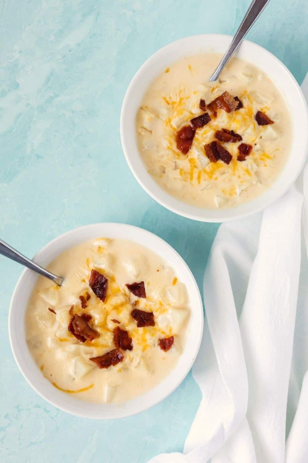 overhead view of two white bowls serving cheesy potato soup made with hash browns in the Crock Pot.