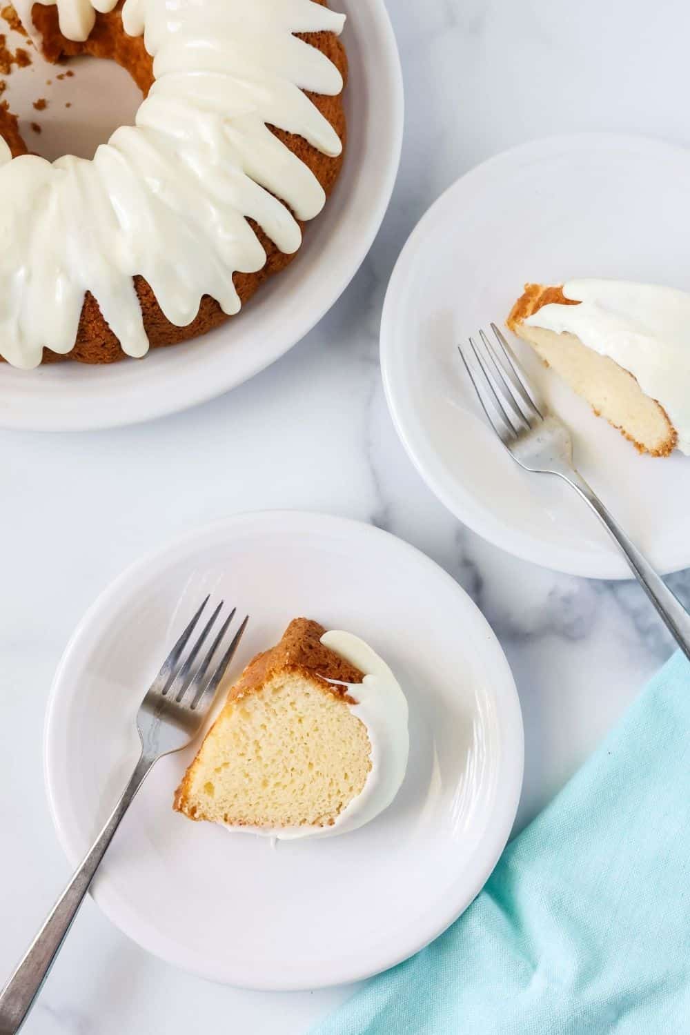 two slices of moist white cake from a mix are served on white dessert plates with forks. A bundt cake is in the corner.