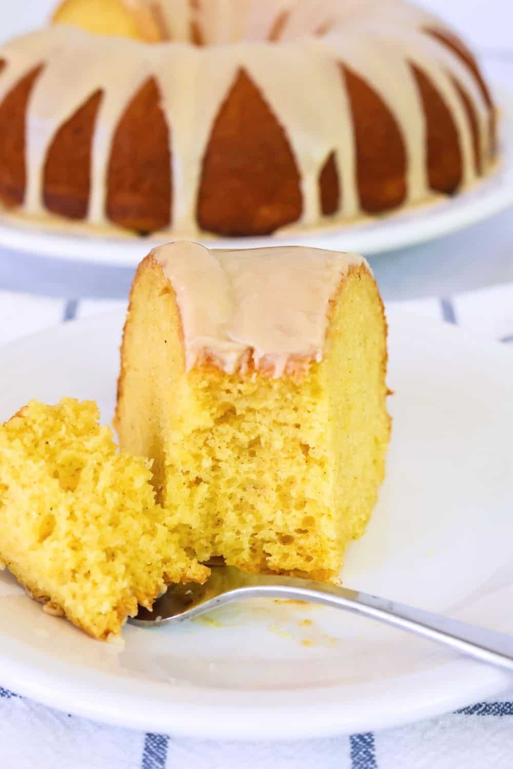 close-up view of a slice of peach cake. A fork has taken a bite out of the cake, showing its moist interior.