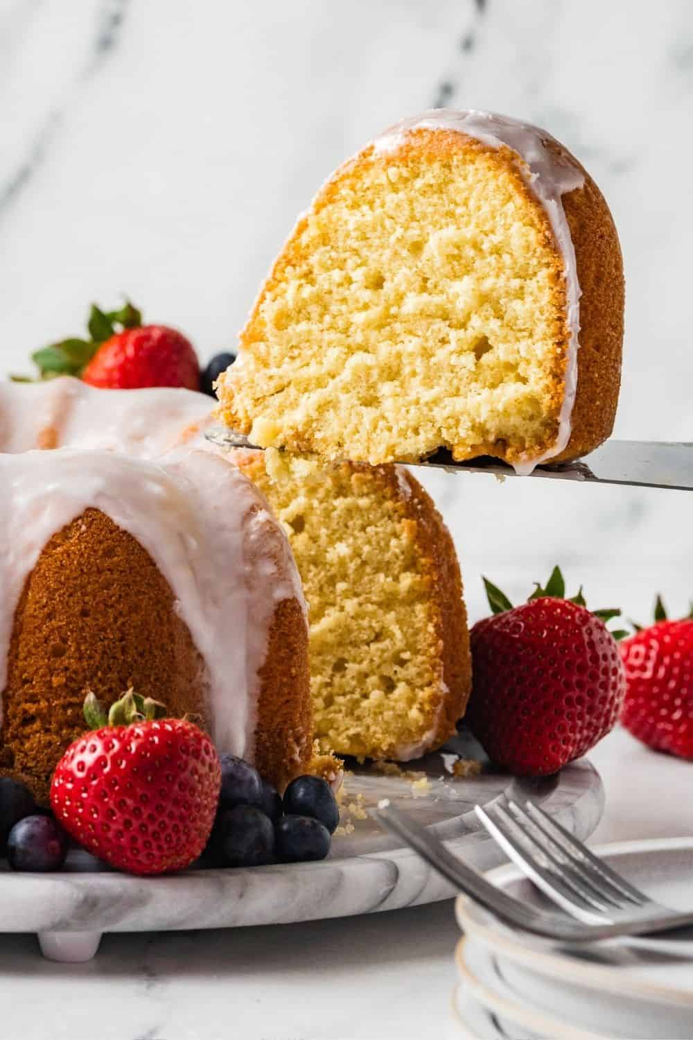 a slice of southern pudding pound cake is being lifted from the cake with a cake server.