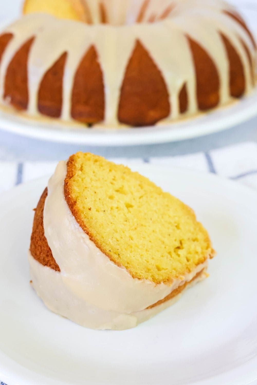 close-up view of a slice of peach bundt cake made with a mix, served on a white plate. The remaining cake is in the background.