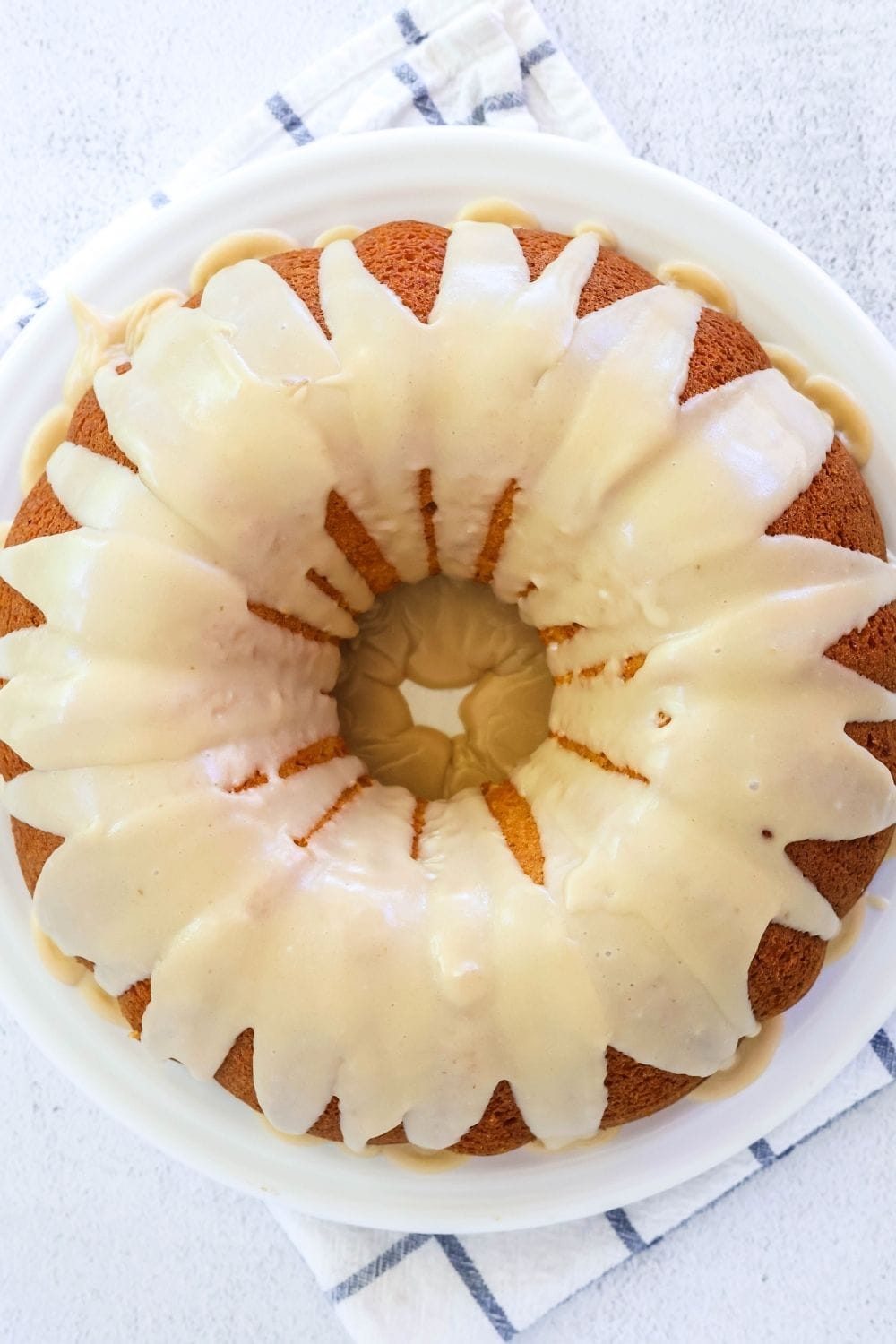 overhead view of a cake mix peach bundt cake topped with brown sugar icing; served on a white platter.