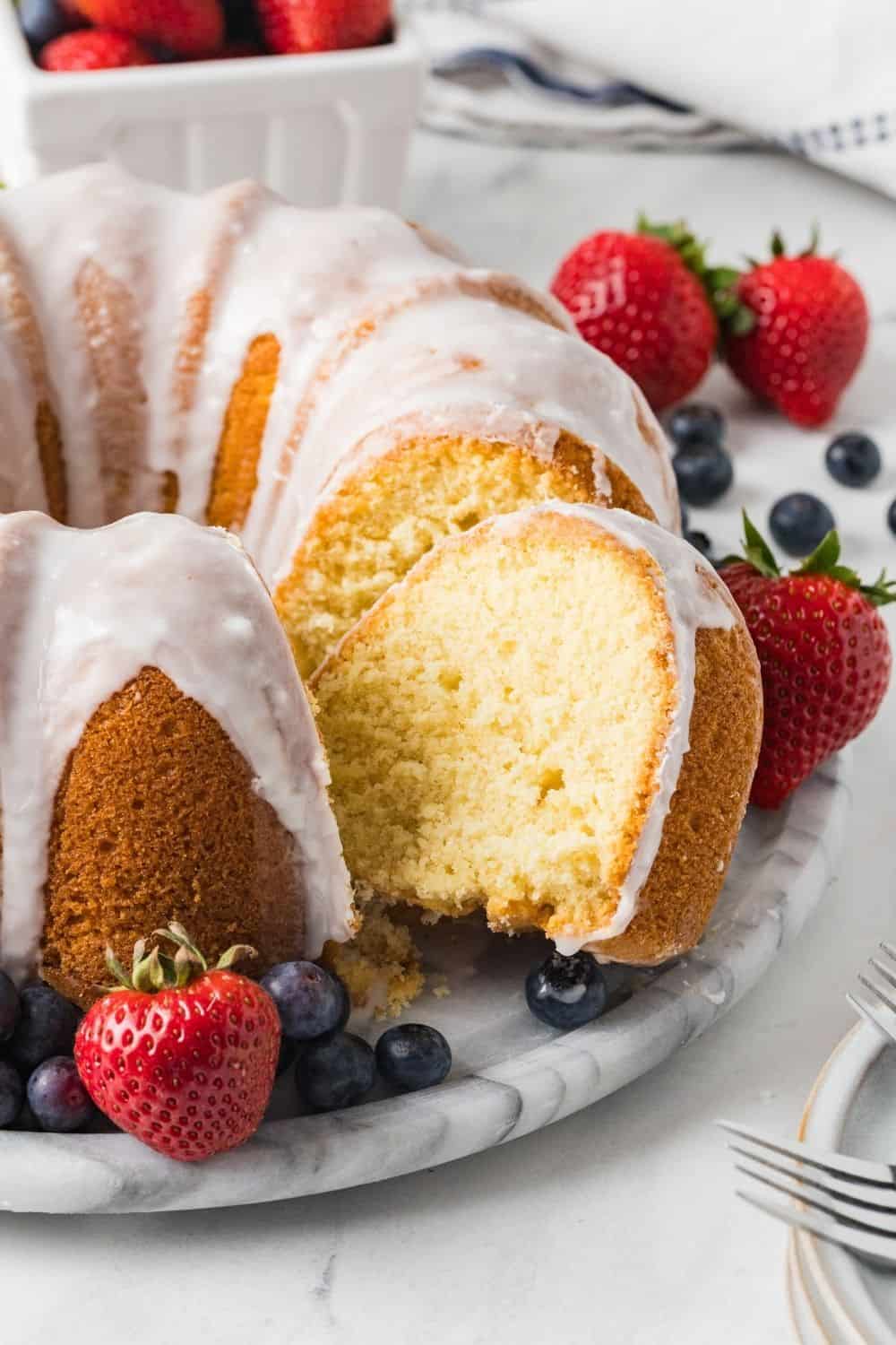 pound cake made with vanilla pudding served on a marble plate. A slice has been removed from the cake.