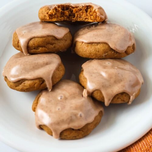 Pumpkin Cookies made from cake mix, served on a white plate. One cookie has a bite taken out of it, showing its soft and moist interior.