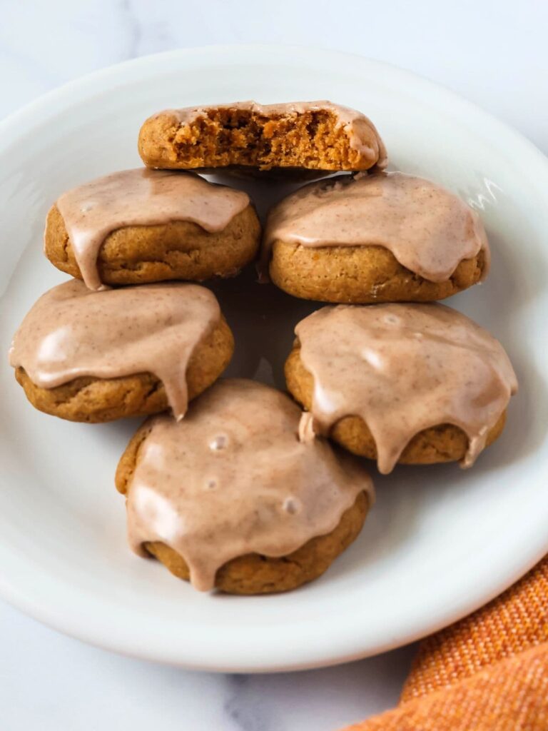 Pumpkin Cookies made from cake mix, served on a white plate. One cookie has a bite taken out of it, showing its soft and moist interior.