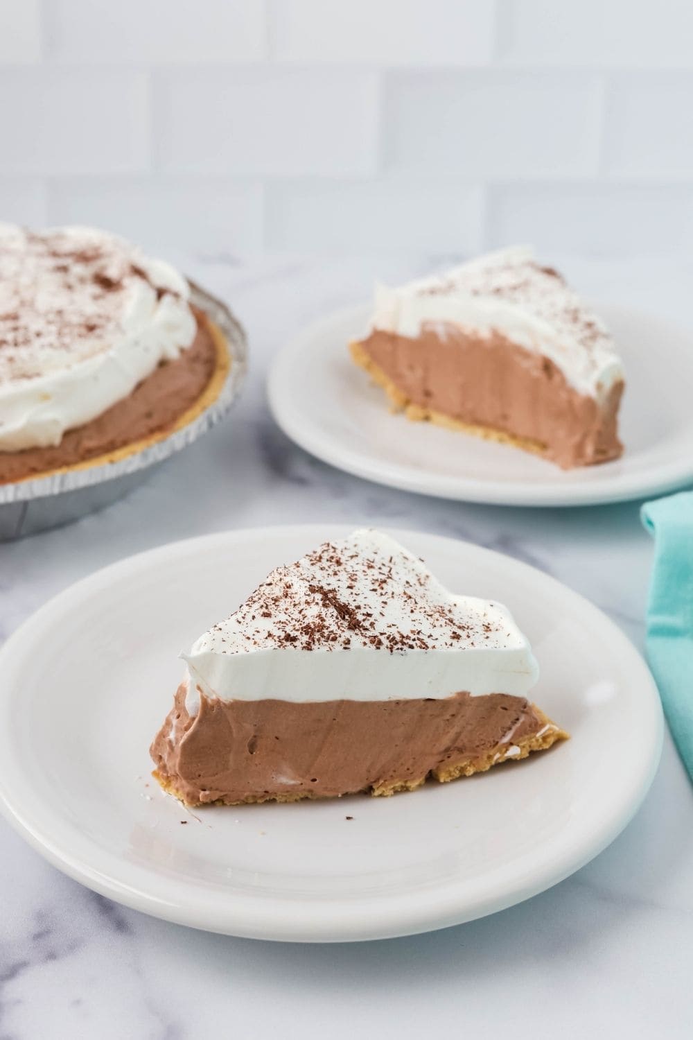side view of two slices of Dream Whip chocolate cheesecake pie. The remainder of the pie is in the background.