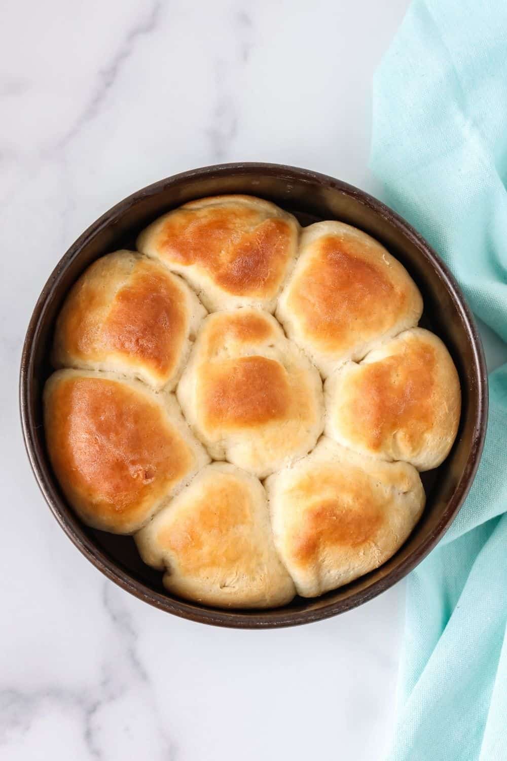 overhead view of a round metal cake pan with freshly baked Bisquick yeast rolls in it.