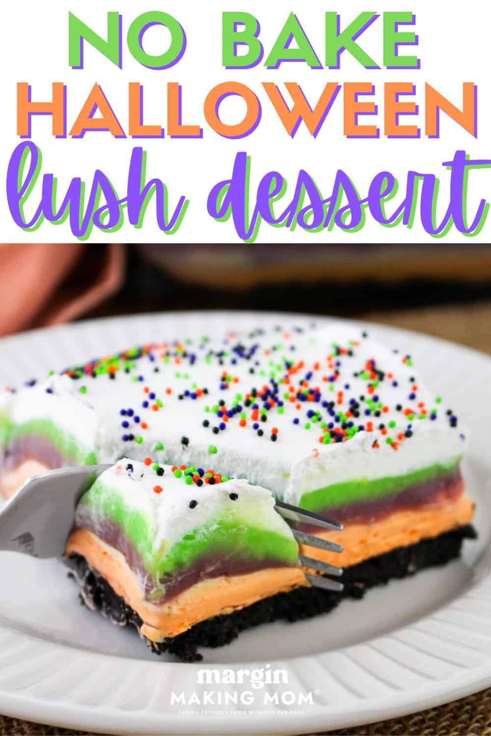 a fork slices a bite out of a square of layered no-bake Halloween lush dessert, served on a white plate.