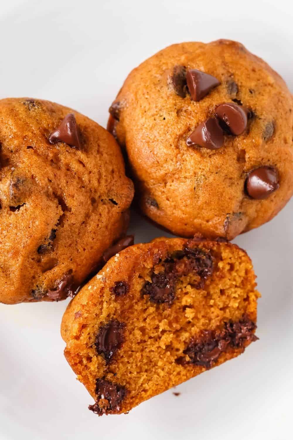 close-up view of pumpkin muffins with chocolate chips, including one muffin that is halved to show the interior.