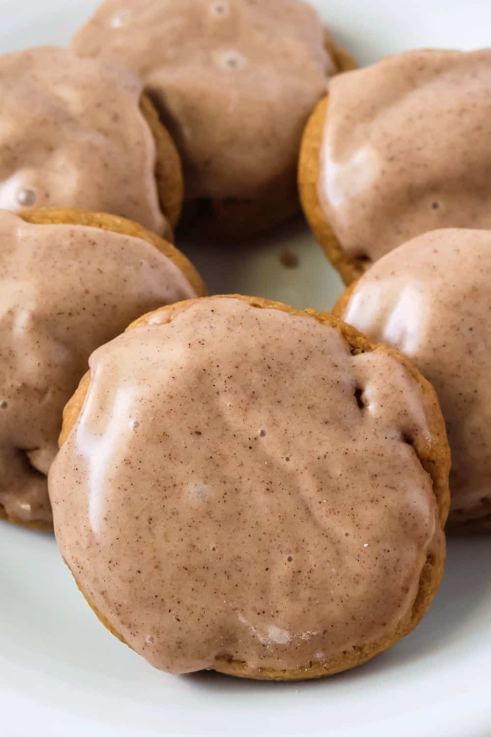 close-up view of several pumpkin cake mix cookies that are topped with a pumpkin-spiced icing that hardens to a smooth finish.