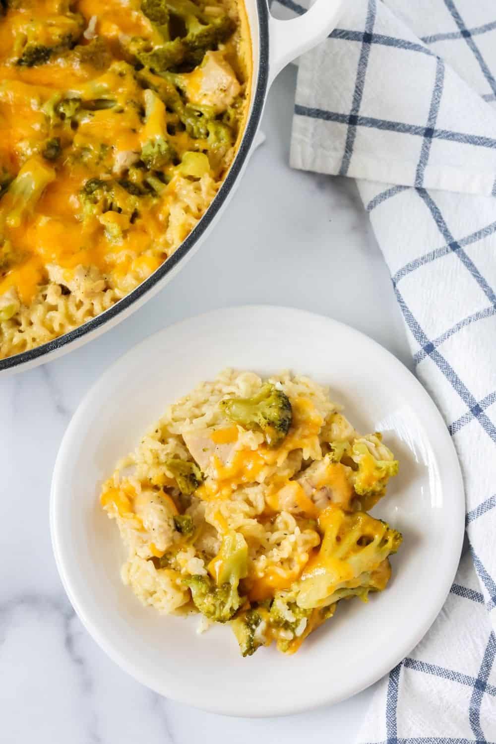overhead view of a white plate serving chicken and rice with broccoli and cheese. The dutch oven of remaining casserole is in the top left corner of the photo.