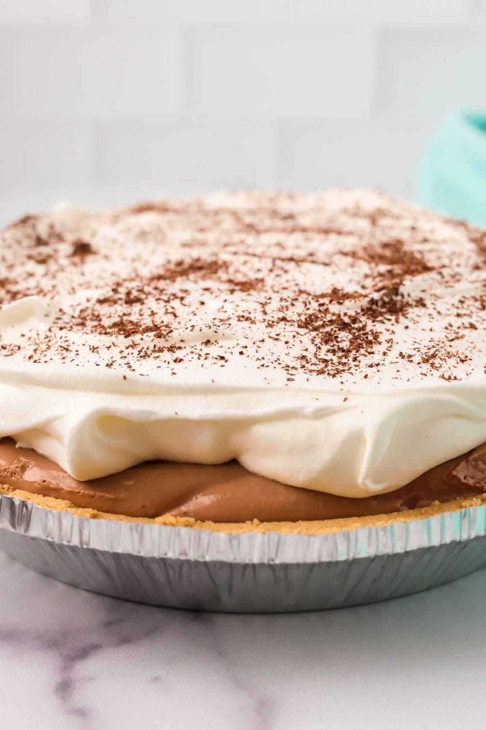 side view of a chocolate cream pie made with Dream Whip and pudding mix, topped with whipped cream and garnished with finely grated chocolate shavings.