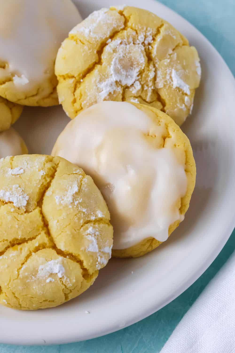close-up of lemon cookies made with boxed cake mix; some are lemon crinkle cookies (without icing) and some are topped with lemon powdered sugar icing.