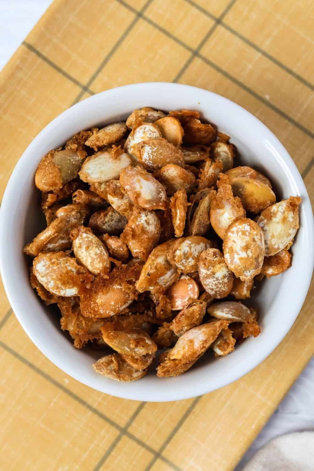 overhead view of a white bowl of brown sugar cookie butter candied pumpkin seeds.