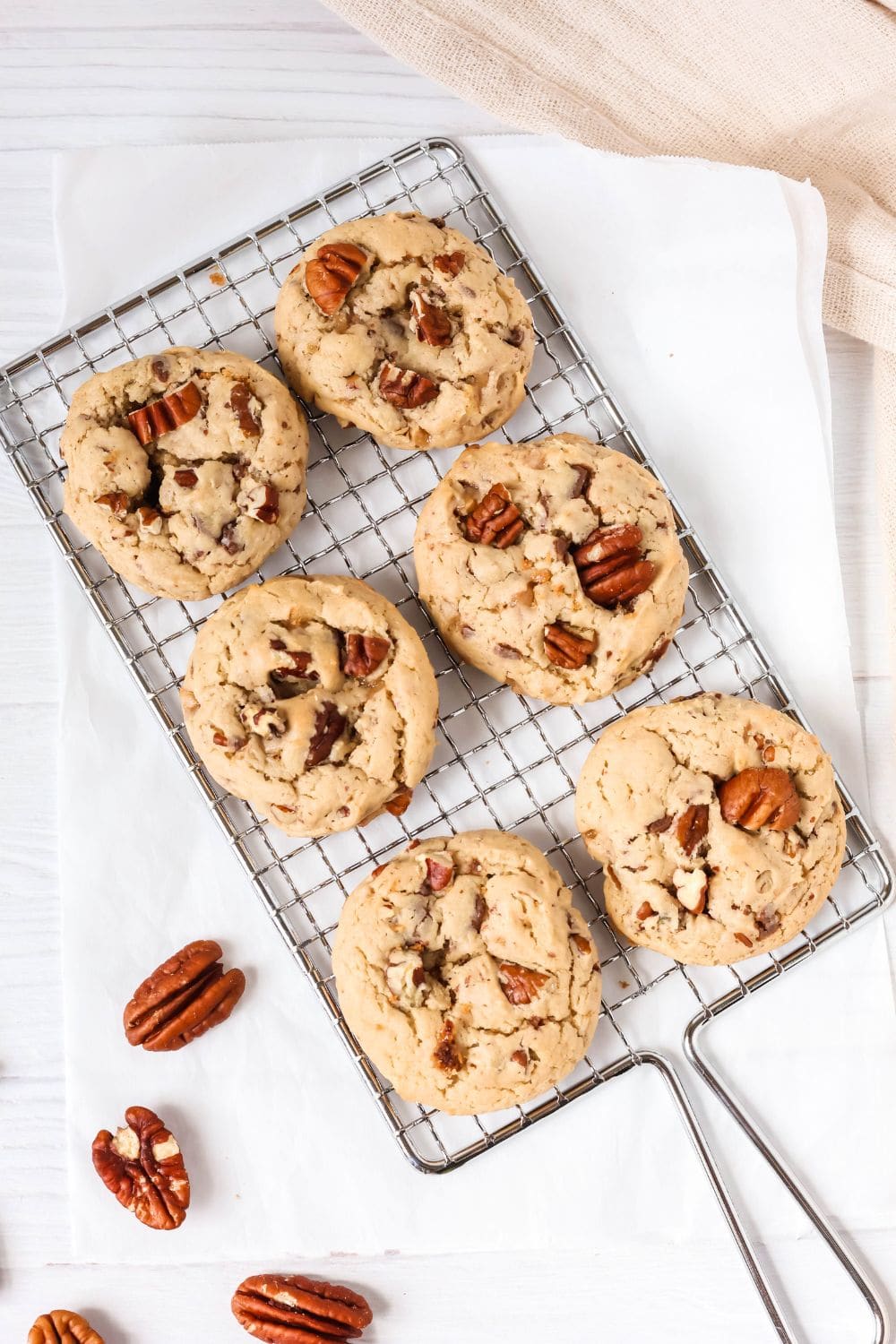 overhead view of a wire rack with six cake mix cookies with pecans on it.