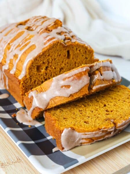 Sliced loaf of cake mix pumpkin bread, showing the details of the moist interior of the bread and the pumpkin spice icing drizzled on top.