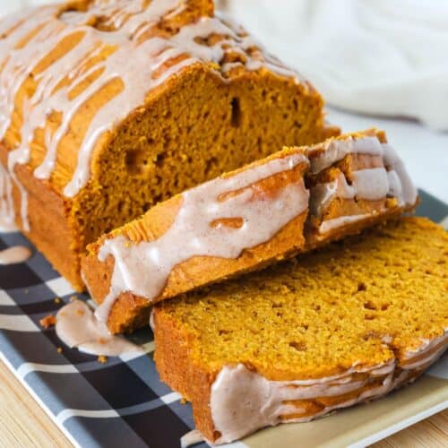 Sliced loaf of cake mix pumpkin bread, showing the details of the moist interior of the bread and the pumpkin spice icing drizzled on top.