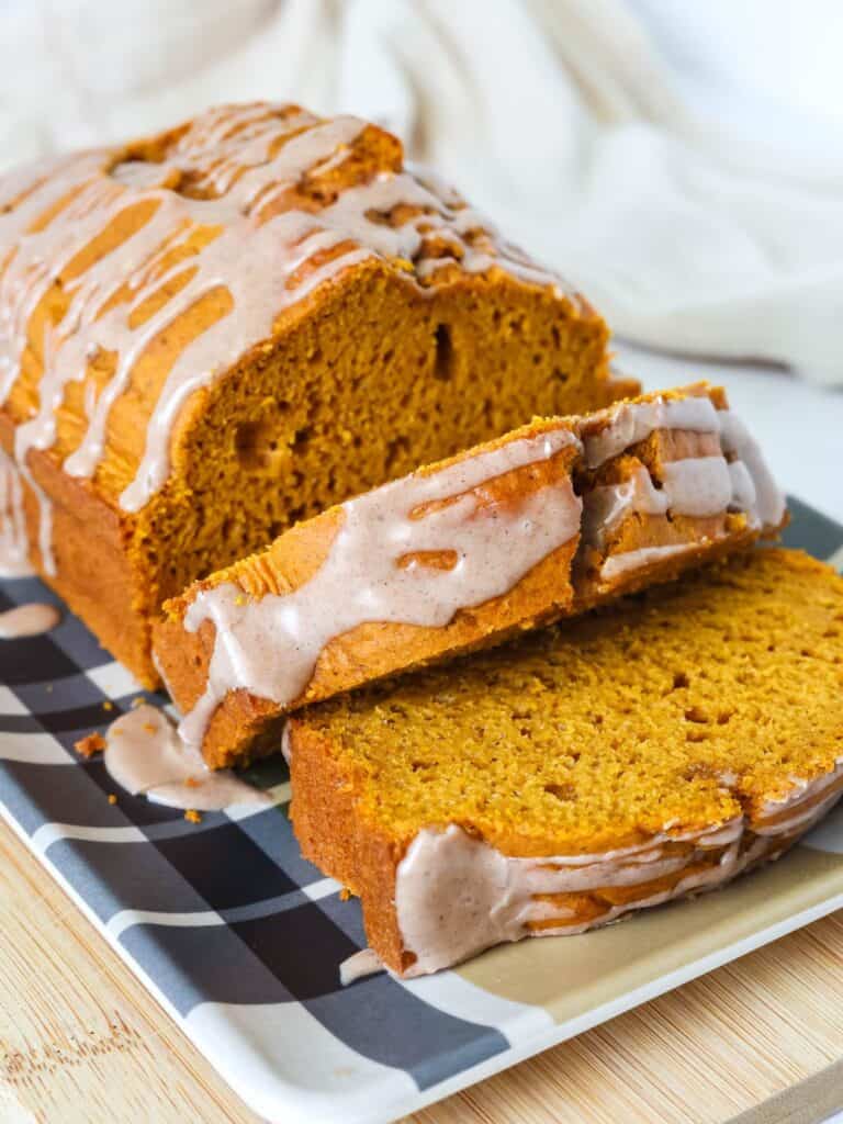 Sliced loaf of cake mix pumpkin bread, showing the details of the moist interior of the bread and the pumpkin spice icing drizzled on top.
