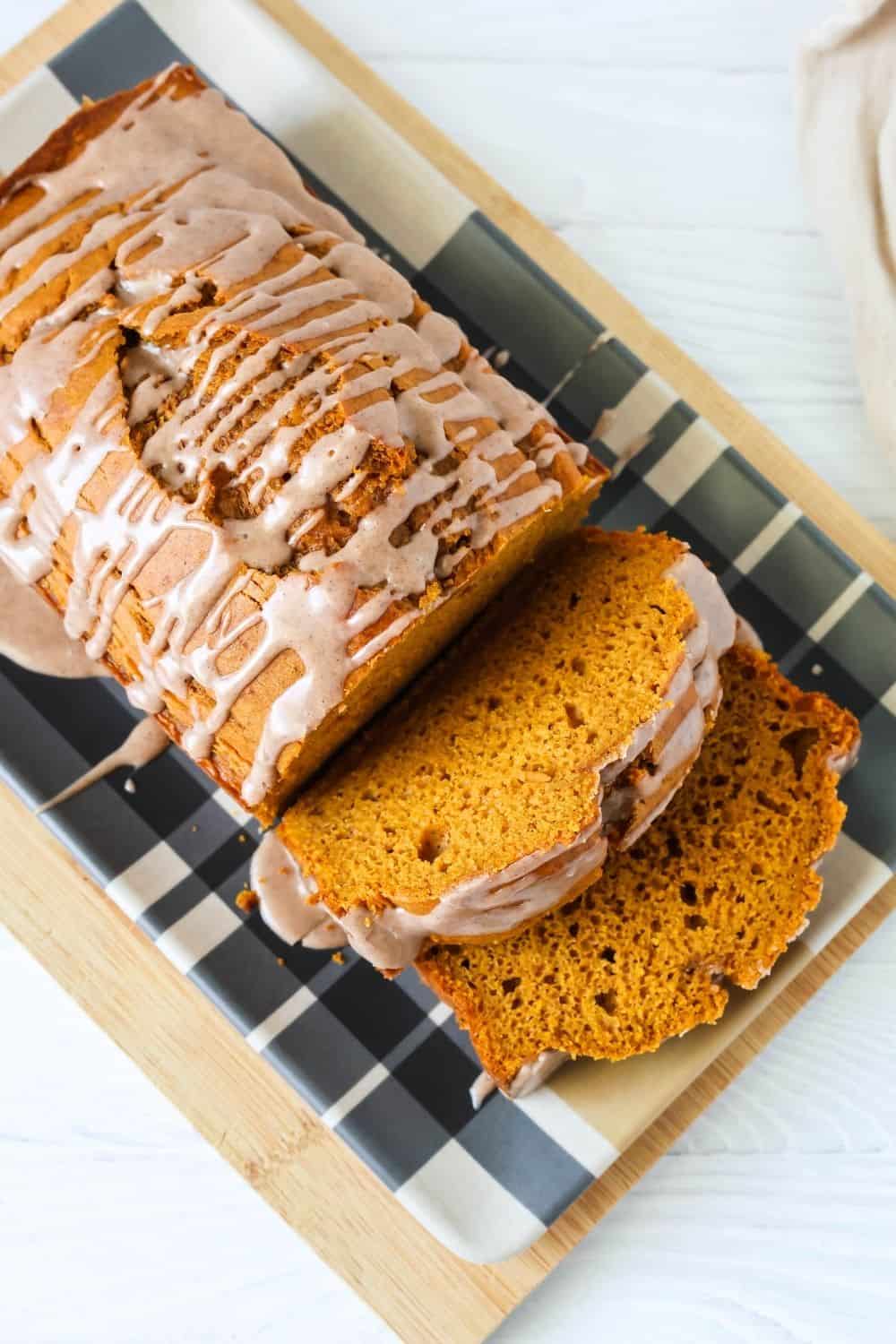 overhead view of cake mix pumpkin quickbread, drizzled with icing, with two slices cut out of the loaf.