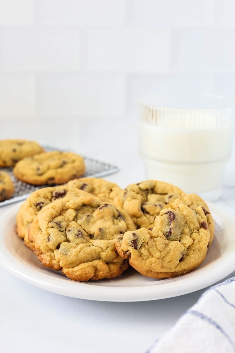 a white plate serves chocolate chip cookies made with instant pudding mix, alongside a glass of milk.