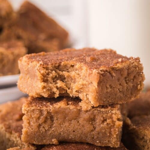 A few churro bars stacked together, one of which has a bite taken out of it, showing the soft and chewy texture.