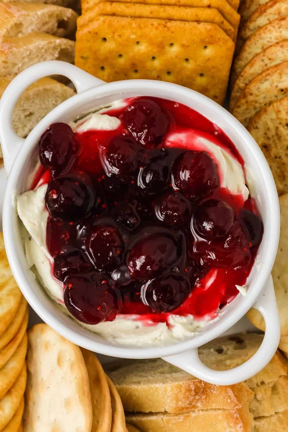 overhead view of a small dish filled with cranberry Boursin appetizer dip, surrounded by crackers.