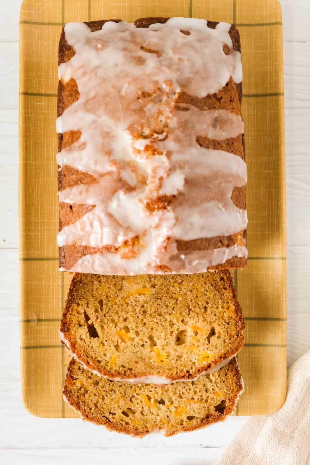 overhead view of a partially-sliced loaf of glazed peach bread made with fresh peaches.
