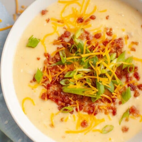 overhead view of a white bowl of Instant Pot potato soup made with frozen hash brown potatoes, garnished with bacon, chese, and green onions.