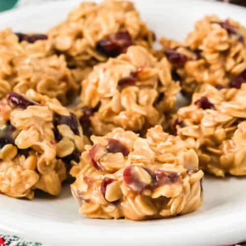 close-up view of no bake cranberry oatmeal cookies on a white plate, showing the detail of the chewy cookies dotted with dried cranberries.